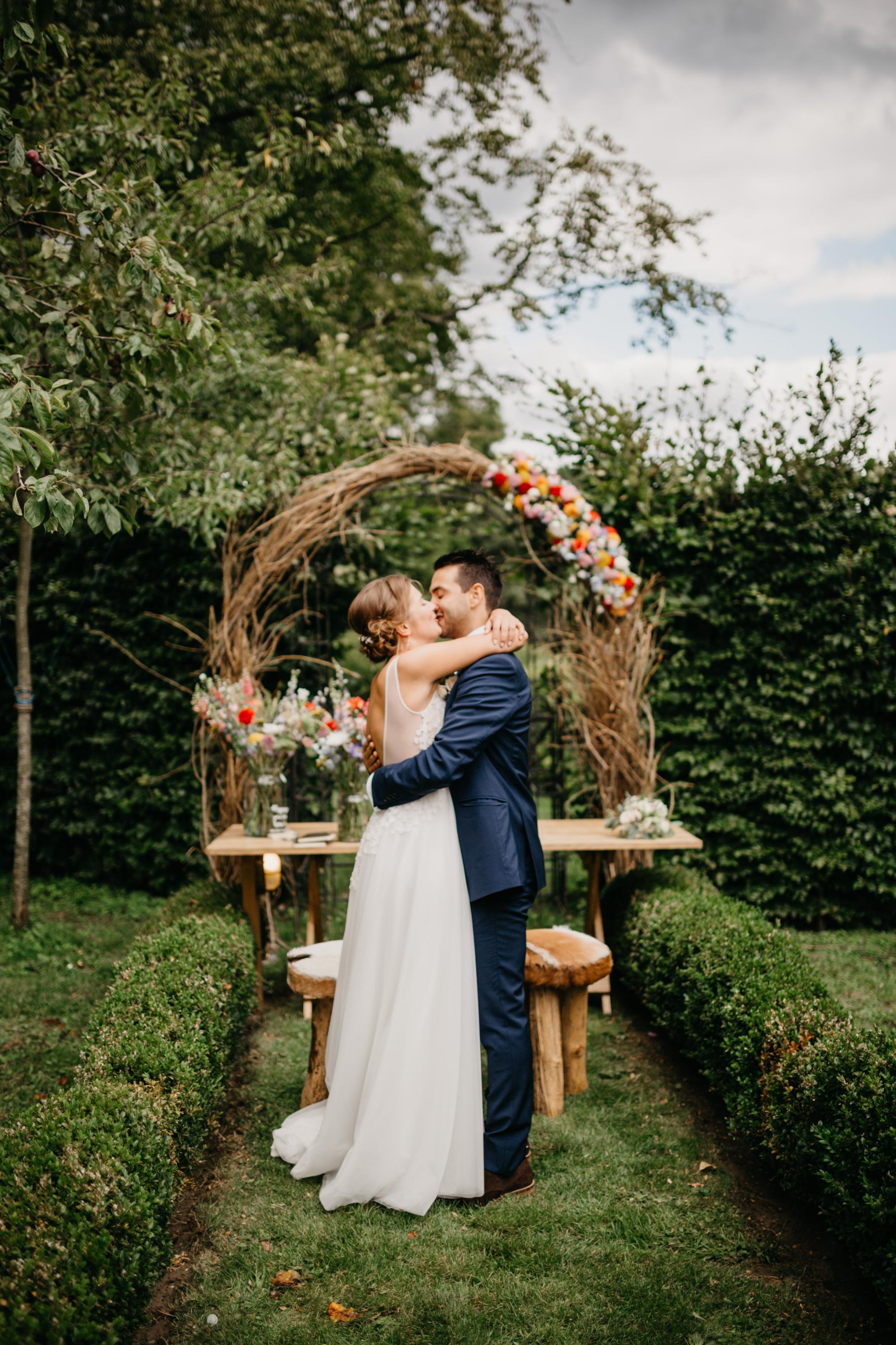 couple kissing in front of a wedding arch